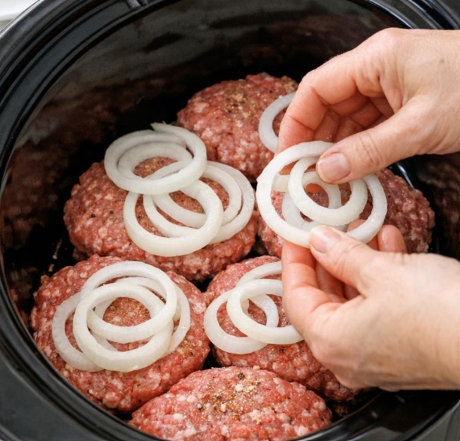 Layer sliced onions atop raw beef patties, combined with 4 ingredients, into slow cooker for a savory feast that disappears faster than anything else