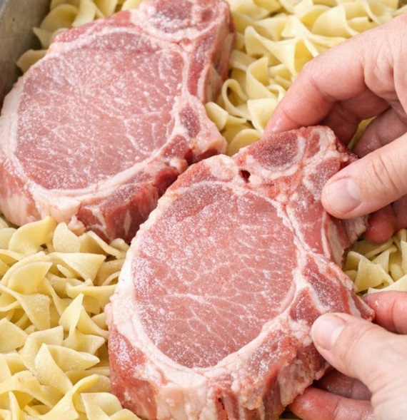 Place raw bone-in pork chops over dry thick egg noodles, paired with 2 more ingredients, into a metal baking pan for a hearty supper that disappears faster than anything else I make